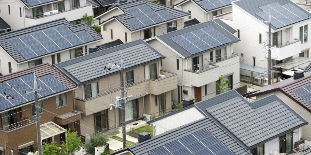 屋根全面にソーラーパネルを載せた戸建てが密集する住宅街を上空から俯瞰した再エネタウンの景観
