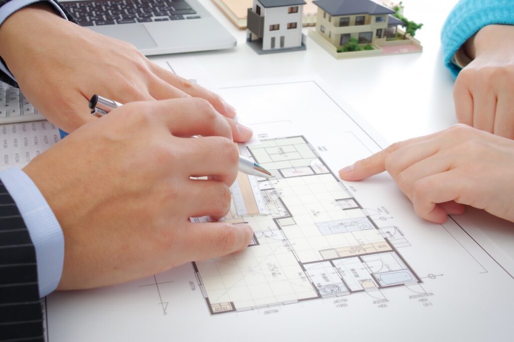 2人の人物が家の見取り図を囲んでいる画像