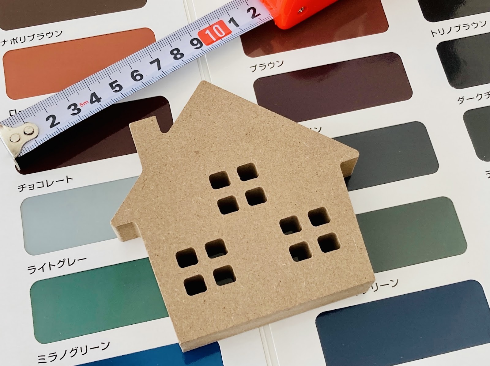 色見本の紙の上にメジャーと家の模型が置かれている画像